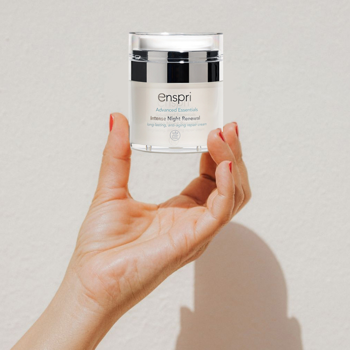 Hand holding a jar of enspri skincare product against a plain background