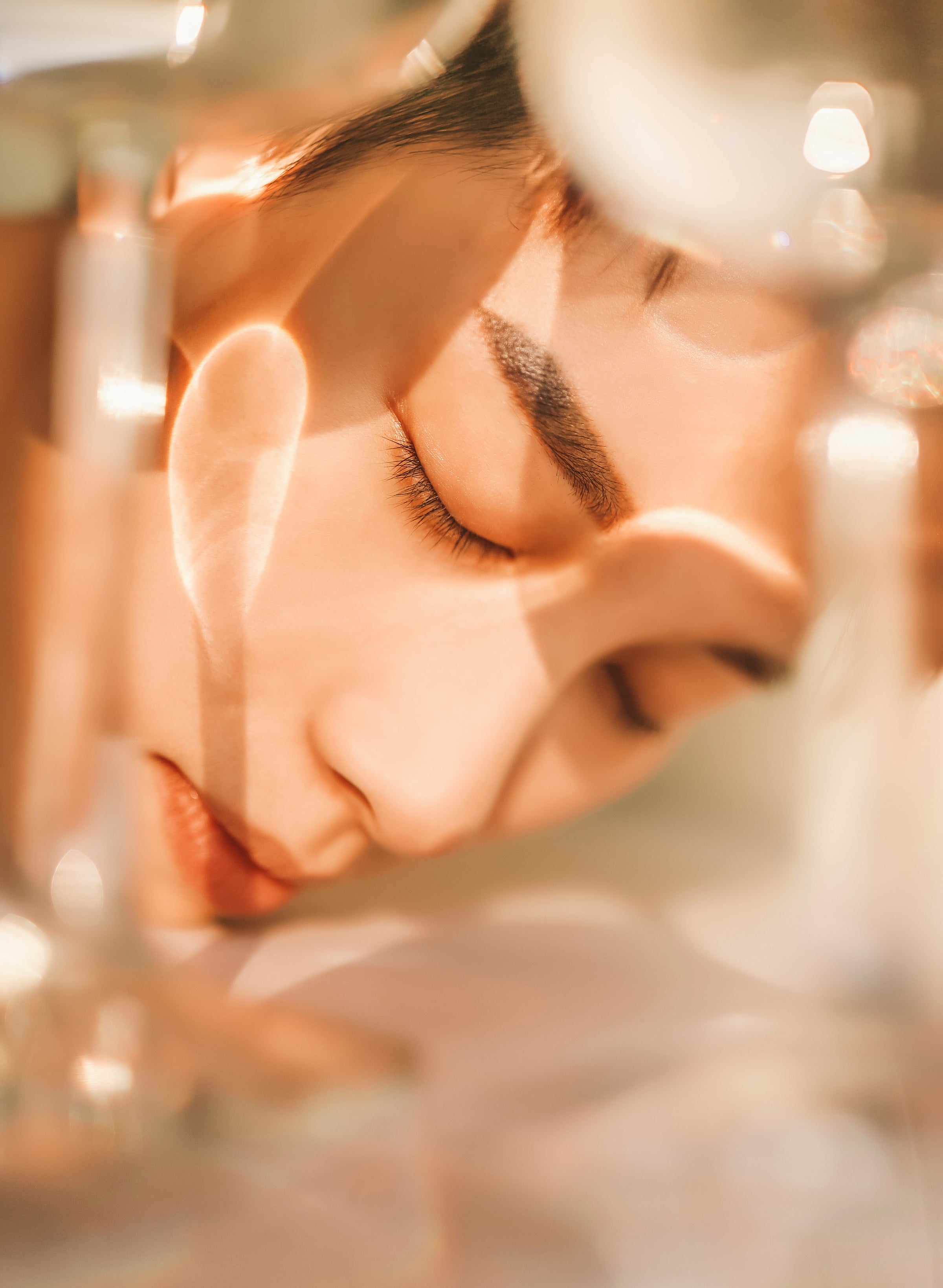 Close-up of a person with glowing, deeply hydrated skin resting peacefully, illuminated by warm, golden light reflections for Enspri Skin Care.