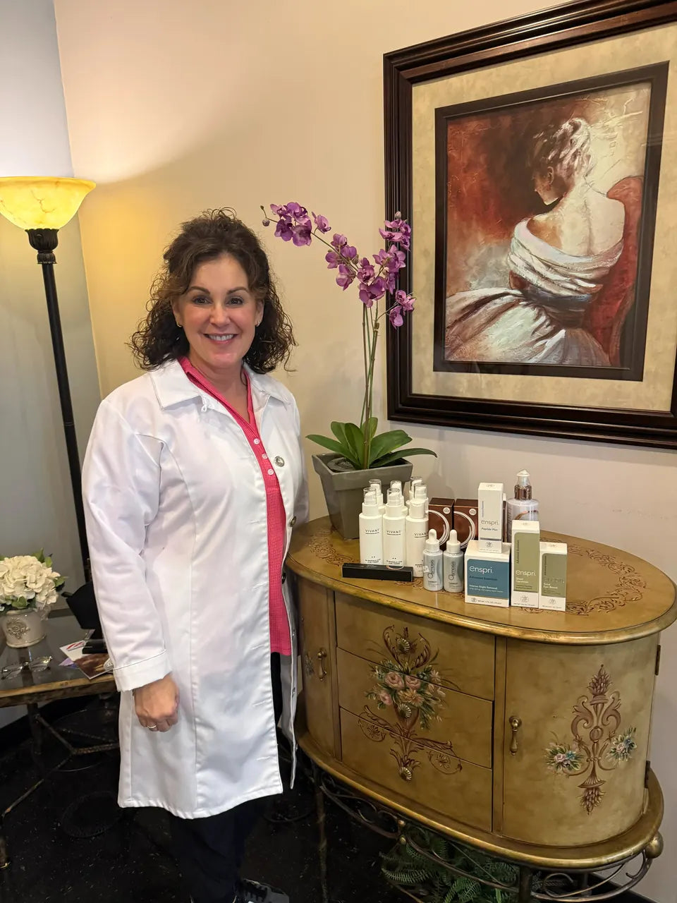 Licensed esthetician Jacqueline DiCicco standing beside Enspri professional biomimetic skincare products in a medical spa treatment room.